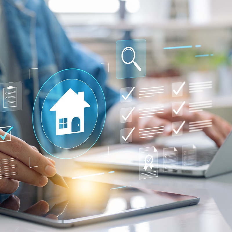 Personne utilisant une tablette et un ordinateur portable avec des icônes virtuelles : maison, loupe de recherche, checklist complétée, documents certifiés. Gestion immobilière digitale.