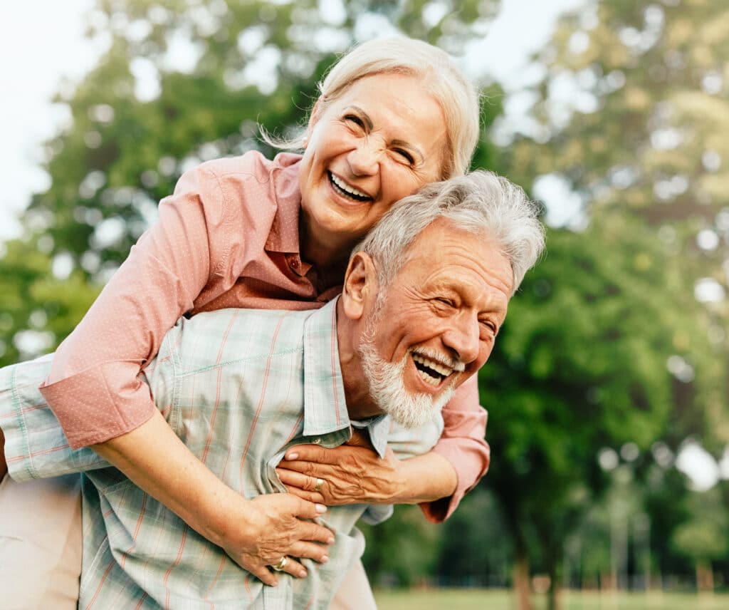 Bonheur Aînés: Couple Heureux et Rieur en Balade au Parc Couple d'aînés joyeux et rieur s'amusant lors d'une balade sur le dos dans un parc verdoyant. Bonheur au grand air.